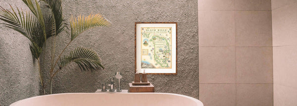Black Hills National Forrest map hanging on the wall over a clawfoot bath tube near a fan plant. 