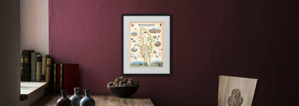 Red Rock Canyon National Conservation Area framed map hanging on a burgundy wall. Print art by Chris Robitaille, the world-renown illustrator, of Xplorer Maps.