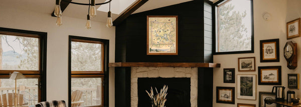 A Yellowstone National Park framed map with hanging on a black wall above a fireplace in a mountain home. 