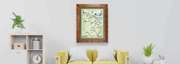 Minnesota State hand-drawn map in earth-tone colors by Xplorer Maps hanging on a wall above a yellow couch. The print is framed in pine with a green frame. 