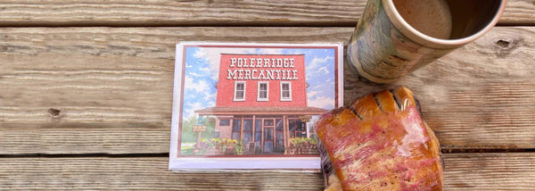 Xplorer Maps notecards featuirng Polebridge Montana. The blank card is sitting next to a travel mug and pastry. 