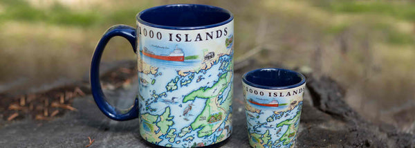 1000 Islands ceramic mug and shot glass sitting on a tree stump. 