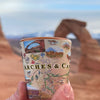 Utah's Arches & Canyonlands National Parks map ceramic s Arches & Canyonlands National Parks map ceramic shot glass. Background: The shot being held overlooking a popular arch rock formation in the National Park.