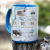 Blue 16 oz Alaska's Denali National Park Coffee Mug sitting on a log in the forest.