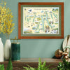 Finger Lakes Framed map hanging on a green wall above a desk. The maps is next to yellow flowers. 