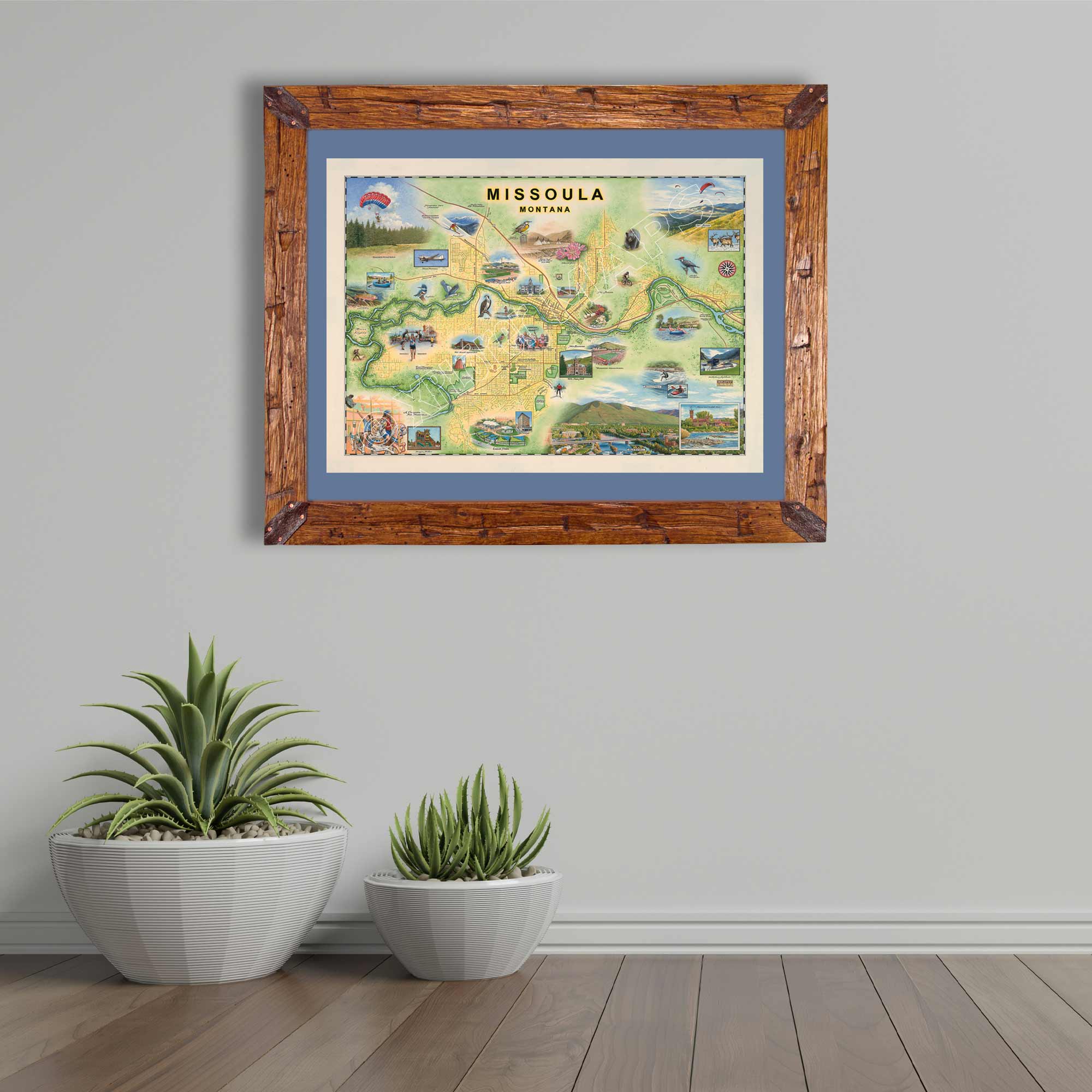 Missoula map print hanging on a gray wall with two potted cacti beneath.