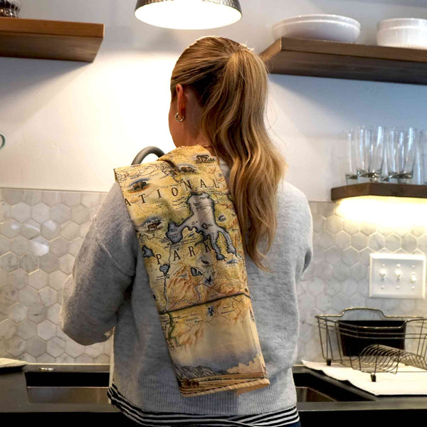 Women washing dishes with a Yellowstone National Park kitchen dish towel  over her shoulder. 