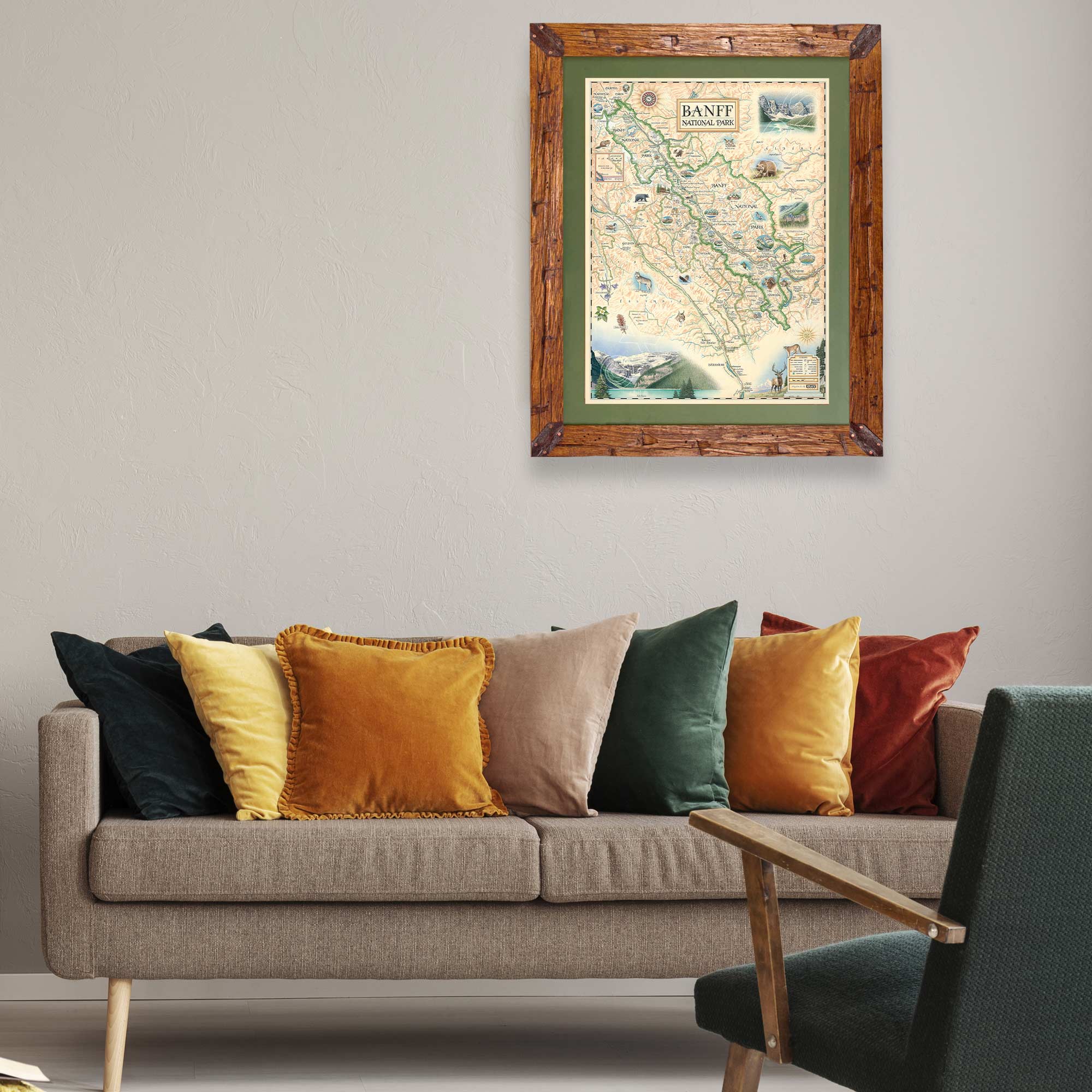 Banff National Park hand-drawn map in a Montana hand-scraped pine wood frame with green mat. The map is hanging over a couch in a living room with colorful pillows.