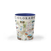 Colorado Map Ceramic shot glass showcases various cities including Denver, Fort Collins, Colorado Springs, Aspen, and Durango. It also features local flora and fauna, such as moose, Rocky Mountain elk, turtles, eagles, and Bighorn Sheep, as well as the indigenous Navajo and Hopi peoples. The map highlights popular activities like hiking, biking, rafting, and skiing.