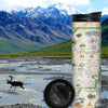 Denali National Park in Alaska with deer crossing the river with snowed covered mountains and green grass in the background. The map features illustrations of the major flora and fauna found in the park, such as grizzly bears, wolverines, moose, lynx, Dall sheep, and many more. Major attractions are illustrated on the map, like the Talkeetna Visitor Center, Denali Visitor Center, Ruth Glacier, and Kahiltna Glacier.