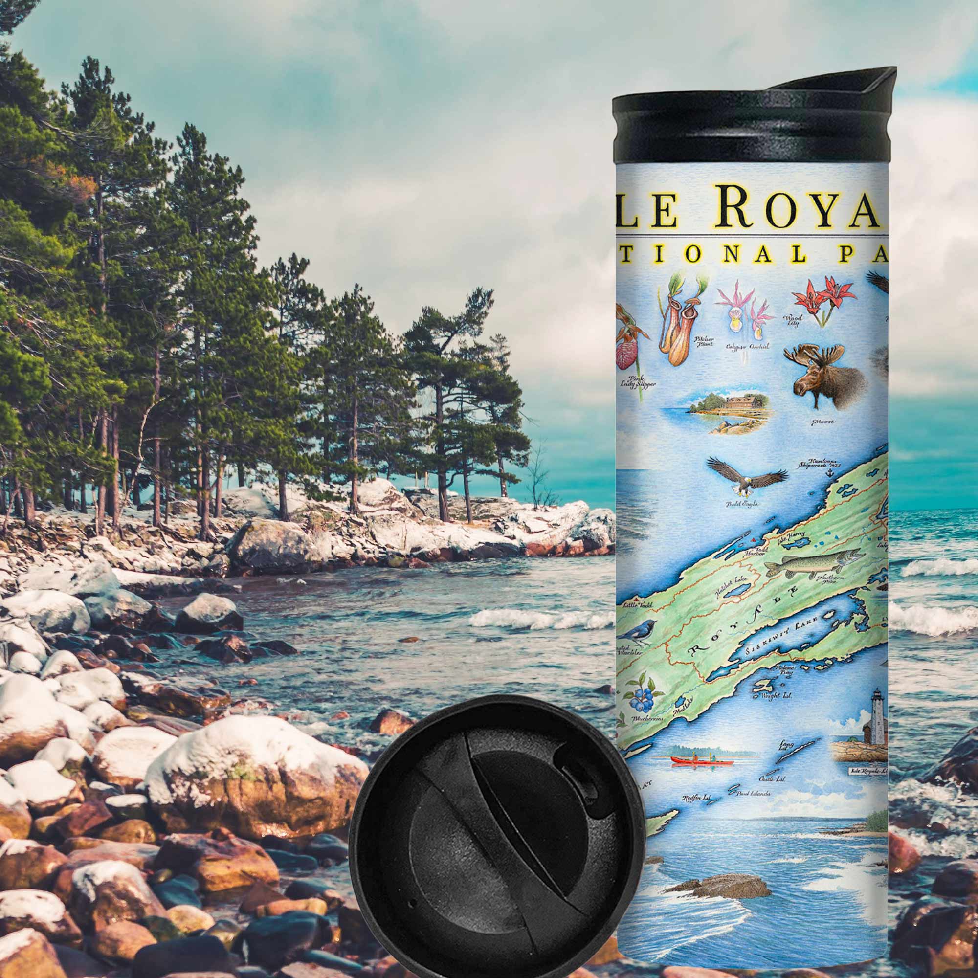 Isle Royale National Park travel mug on a rocky beach near water and pine trees. The map features flora and fauna such wolf, moose, Pink Lady Slippers, and Thimbleberries. Other illustrations include Lookout Louise, Rock of Ages Lighthouse, and the Rocky Harbor Lodge.