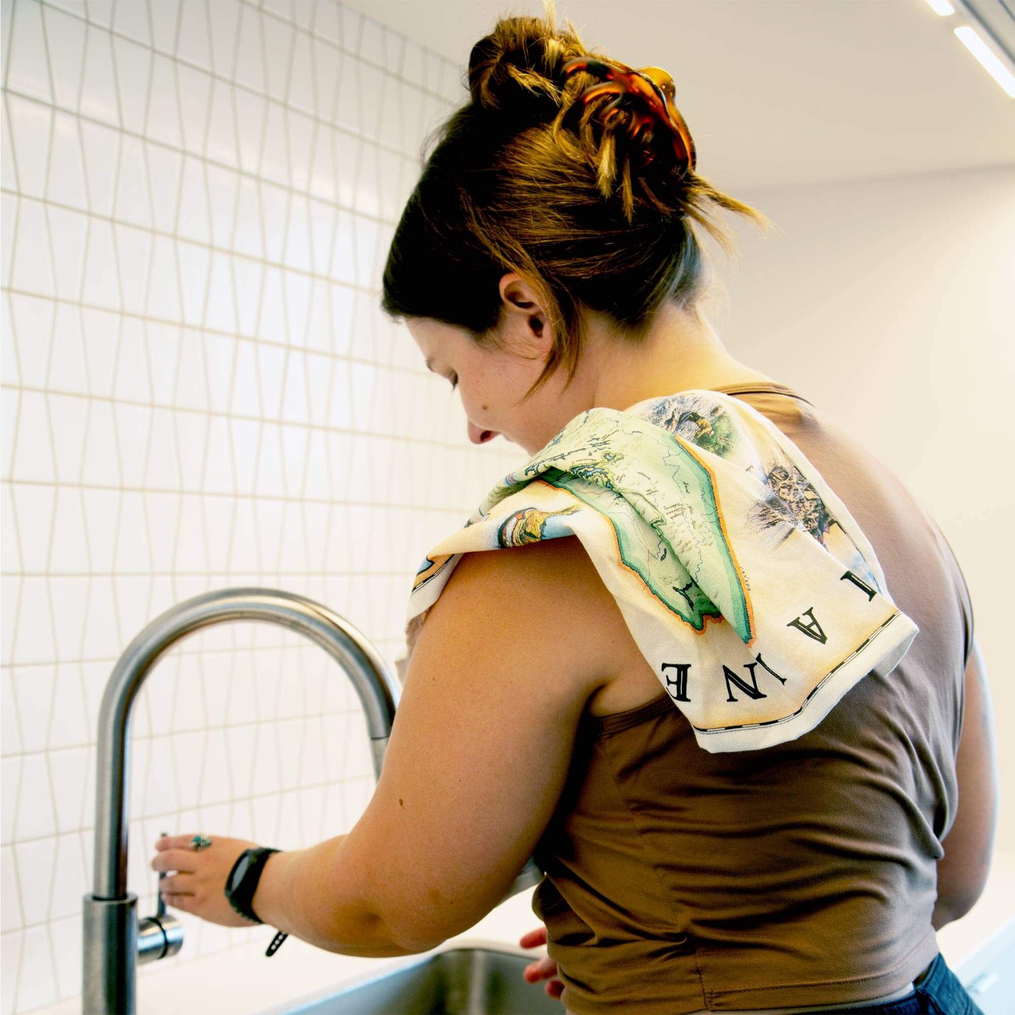 Maine State Map kitchen dishtowel hanging over a women's shoulder while washing dishes.