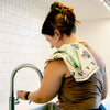 Maine State Map kitchen dishtowel hanging over a women's shoulder while washing dishes.