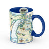 Blue 16 oz Michigan state ceramic coffee mug. The cup features moose, elk, bear, great lakes, lighthouse, fish, Kalamazoo windmill, Detroit, Lansing, Stevie Wonder, Ford Model T, cherries, wolverine, loons, and owls.