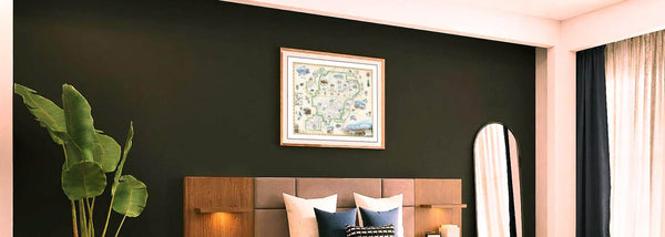 This Lithographic map art print features a framed hand-illustrated map of Denali National Park. The picture map is hanging over a bed on a dark green wall.  