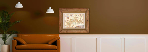 A Grand Canyon National Park framed map over a chocolate-colored leather sofa. Chris Robitaille, the world-renown illustrator is shown to the right drawing on top of his car. Each map is hand-illustrated original art.