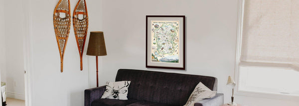 Rocky Mountain National Park hand-drawn map hanging on a wall over a gray couch in a living room. 