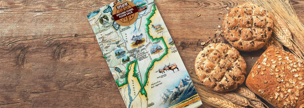 Xplorer Maps Grand Teton Kitchen Tea Towel. The dish towel is sitting on a wood counter next to baked goods. 