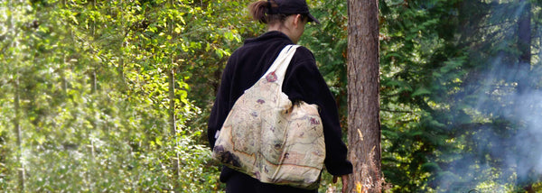 Women with an Xplorer Maps Montana pouch tote bag in the forest. 