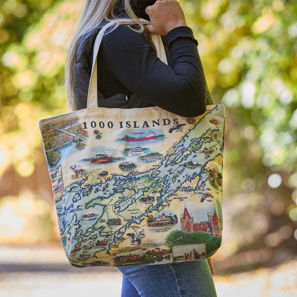 Tote bag with a map design of the 1000 Islands held by a person outdoors.