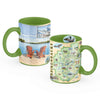 Two green ceramic mugs with printed scenic artwork on a white background. One mug shows a lake, mountains, and two Adirondack chairs on a wooden deck, and the other shows a detailed map labeled Adirondacks with small illustrated icons.