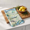 Map of Alaska on a wooden cutting board with lemons and herbs on a kitchen counter.