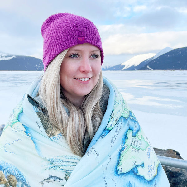 Woman wrapped in a map blanket with snowy mountains in the background