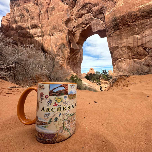 Arches and Canyonlands National Park ceramic mug place in the red stand of the National Park. In the background is stone arches. 