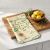 Map-themed towel on a wooden cutting board with lemons and herbs on a kitchen counter.