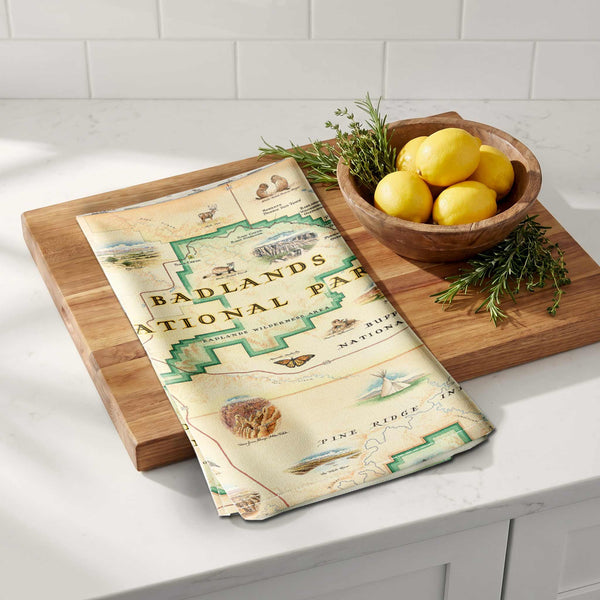Map-themed towel on a wooden cutting board with lemons and herbs on a kitchen counter.
