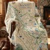 Map-themed blanket with Banff National Park design draped over a chair in a cozy room.
