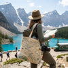 Person with a Banff National Park tote bag standing in front of a scenic mountain lake.