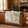 Map-themed blanket on a brown leather sofa in a cozy living room with a fireplace.
