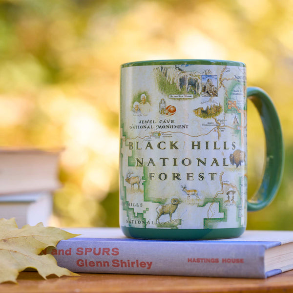 Mug with Black Hills National Forest design on a book with a blurred natural background