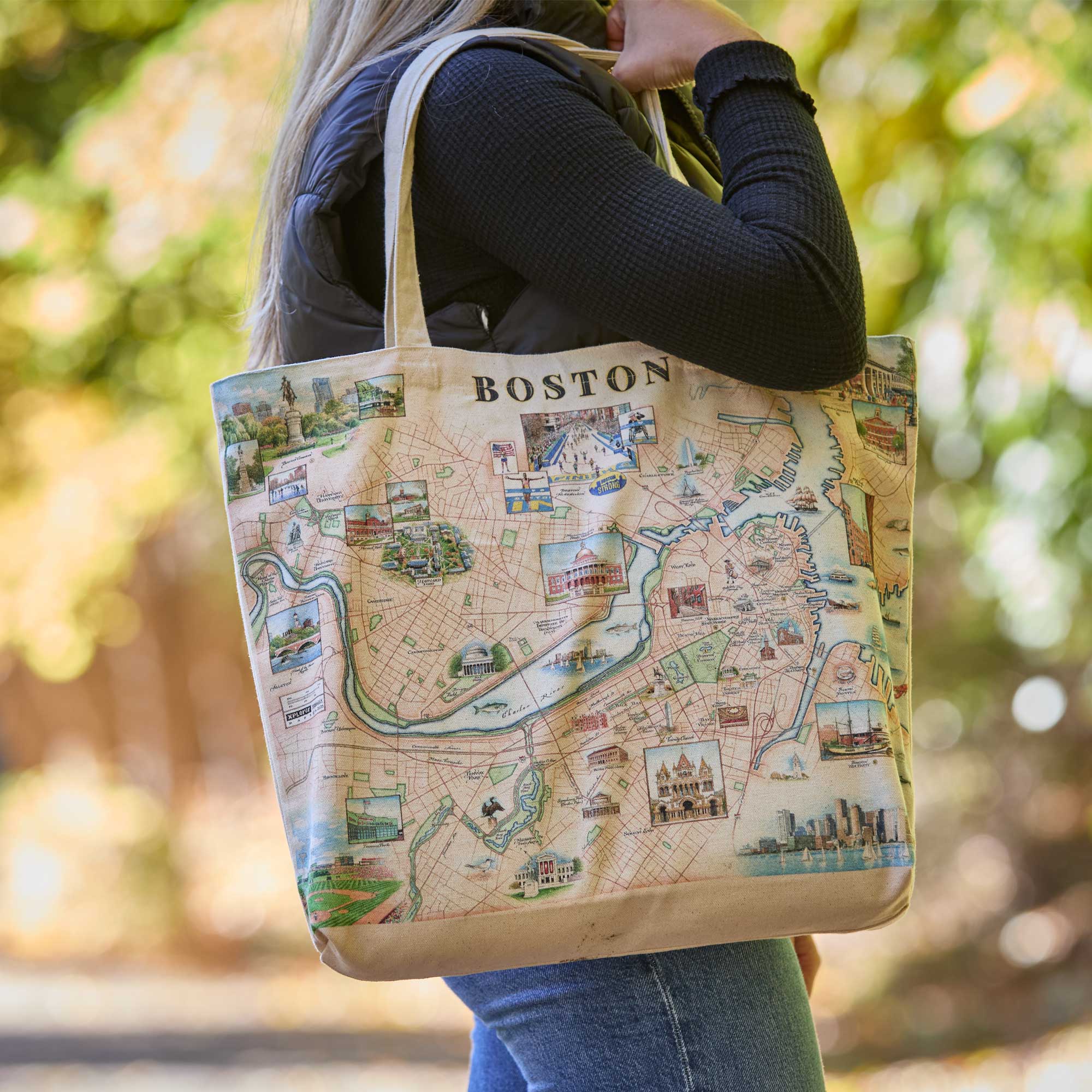 Tote bag with a map design of Boston held by a person outdoors.