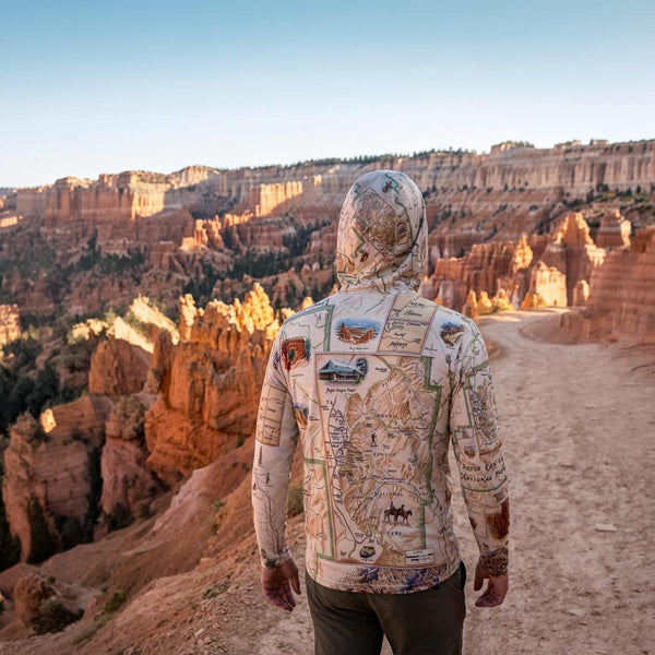 Person wearing a Bryce Canyon sun shirt hoodie with map design standing in a canyon landscape