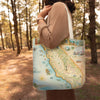Person holding a tote bag with a map design of California in a forest setting
