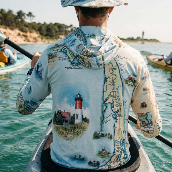 Person wearing a Cape Cod map-themed sun shirt on a boat in a body of water with trees in the background