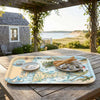 Decorative map tray of Cape Cod with food on a wooden table outdoors, featuring a scenic design.