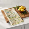 Wooden cutting board with a map-themed towel and a bowl of lemons on a kitchen counter.