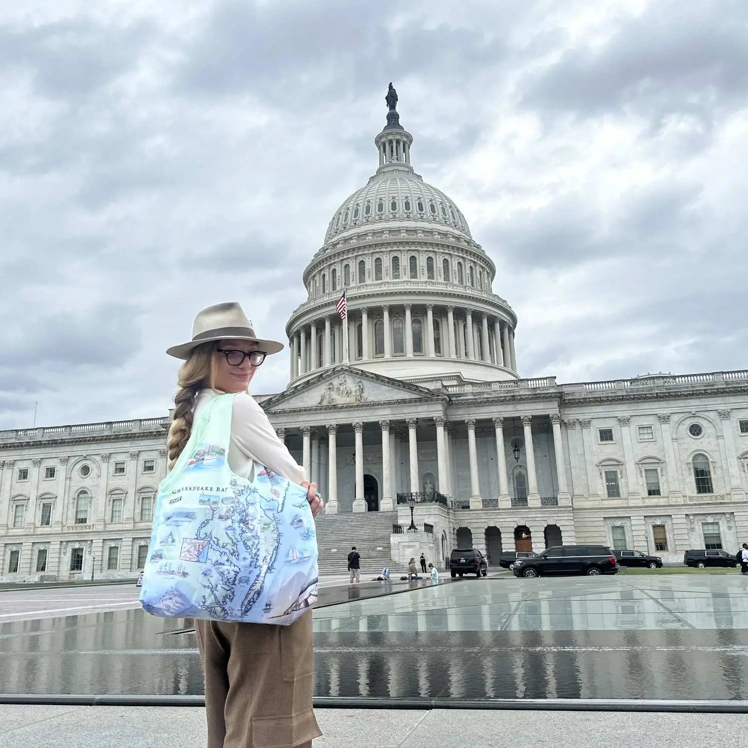 A women standing in front of the Capitol building. She is carrying  a Chesapeake Bay pouch tote bag. 