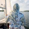 Person wearing a Chesapeake Bay map-themed Sun shirt hoodie on a sailboat with water and sky in the background