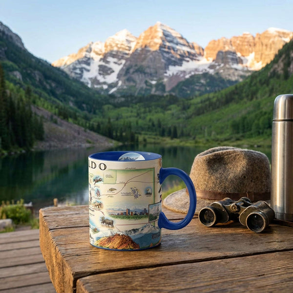 Mug with Colorado map design on a wooden table with scenic mountains and lake in the background