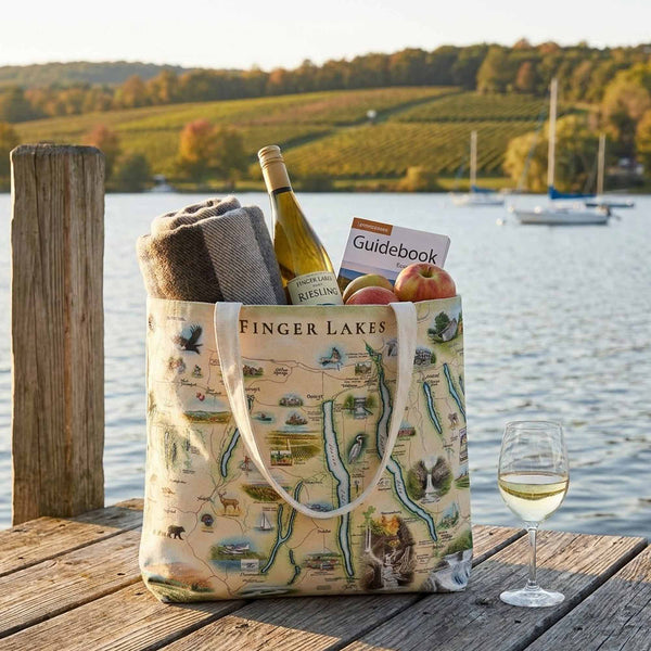 Finger Lakes themed tote bag with wine, apples, and a glass of wine on a dock by a lake.