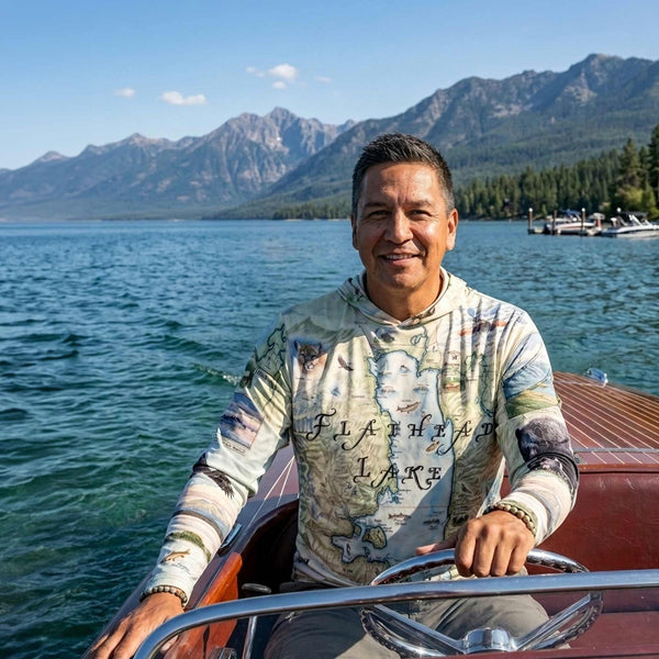 Man on a boat in a lake with mountains in the background on Flathead Lake wearing Sun Shirt 