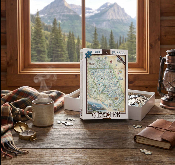 A 1000-piece jigsaw puzzle box labeled 'GLACIER' stands on a rustic wooden table in a cabin setting, with an open box of loose puzzle pieces beside it. A mug, scarf, lantern, notebook, and mountain landscape visible through the window create a cozy outdoor-themed scene.