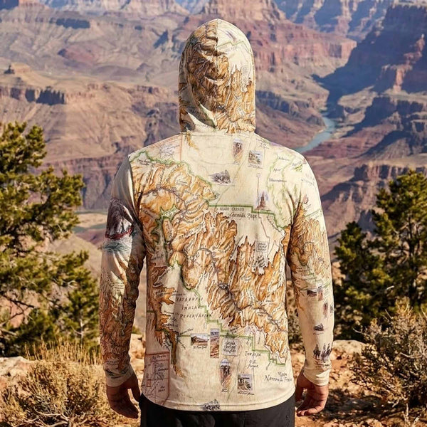 Person wearing a hoodie with a map design standing in front of a canyon landscape