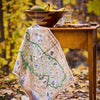 Map-themed towel draped over a wooden table with a bowl of fruit in an autumn setting