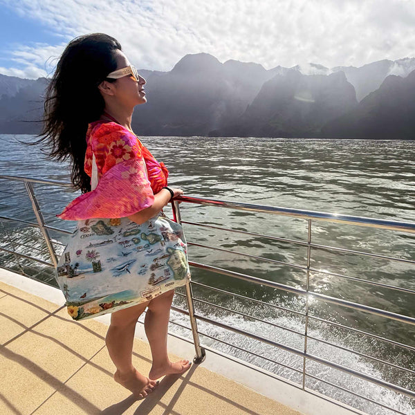 Woman in a colorful outfit standing on a boat with a scenic mountain view in the background