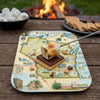 S'mores with a serving tray map of Wisconsin design on a wooden table with a campfire in the background.